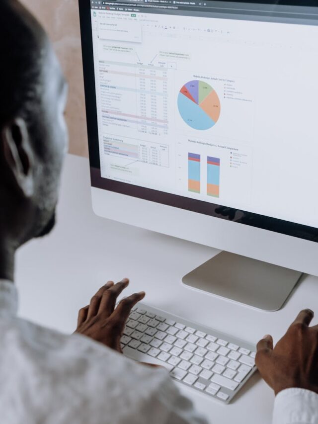 Businessman analyzing charts and data on desktop computer in office setting.
